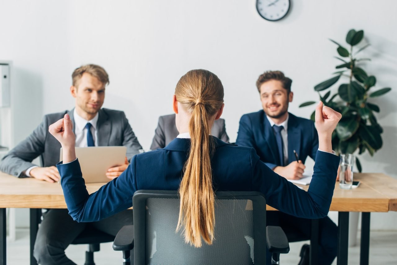 selective-focus-of-employee-showing-yeah-gesture-near-smiling-recruiters-at-table.jpg